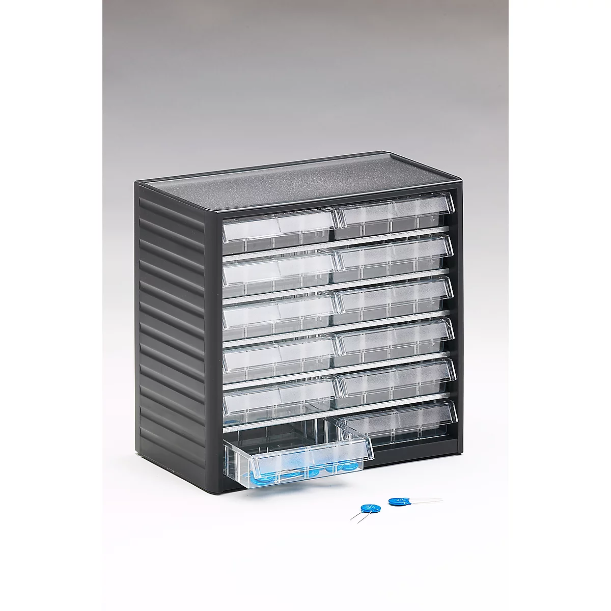 Dark drawer box with transparent drawers. One drawer is slightly open, next to it are blue objects.