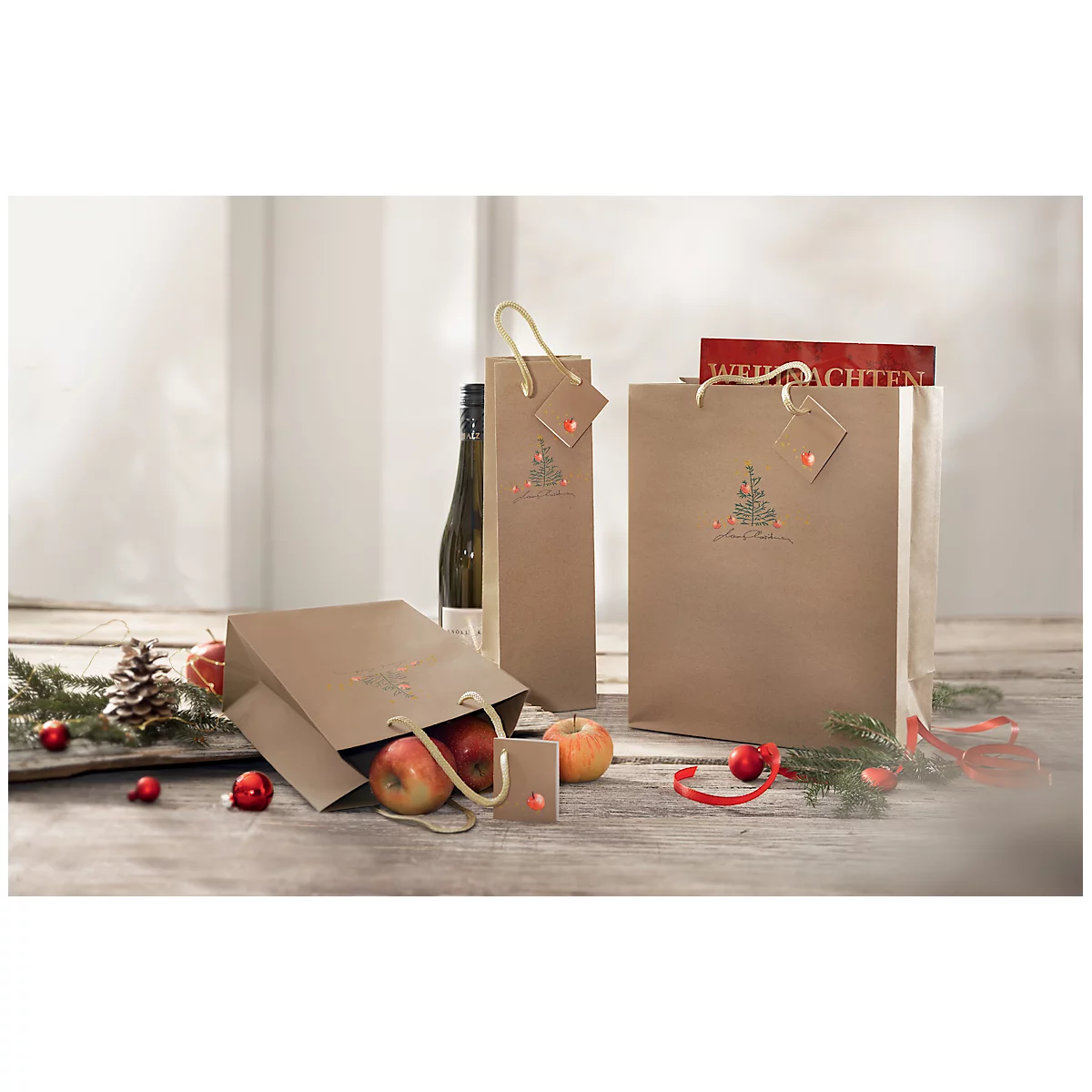 Various paper bags with apples and a wine bottle on a wooden table, decorated with Christmas accessories. One bag says 'Christmas'.