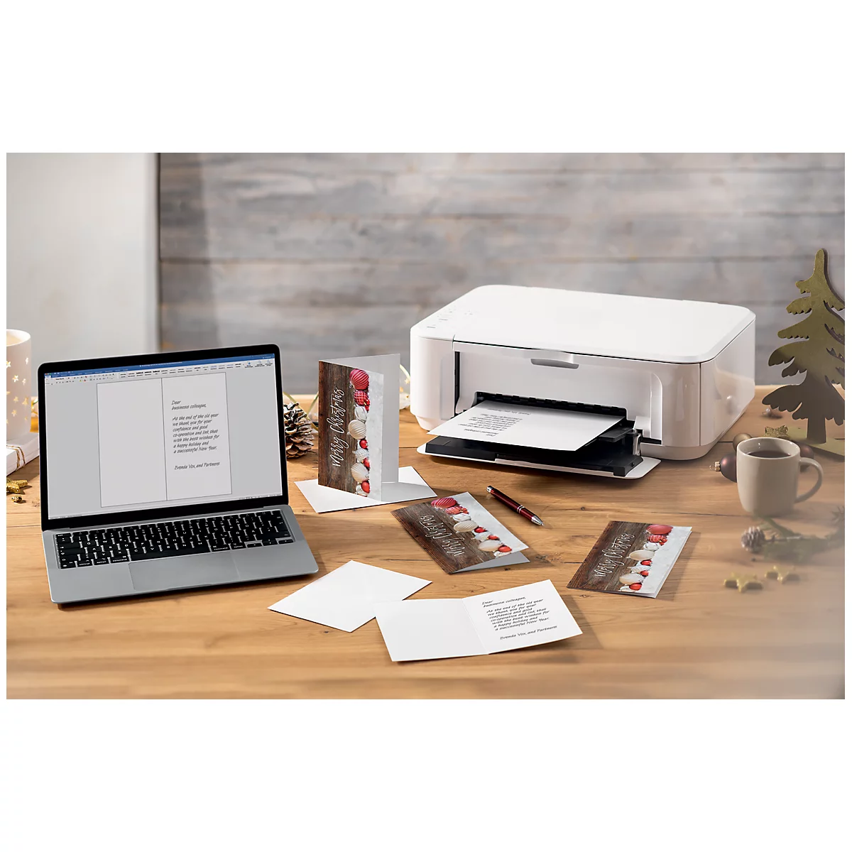 Laptop and printer on a desk surrounded by greeting cards and decoration.