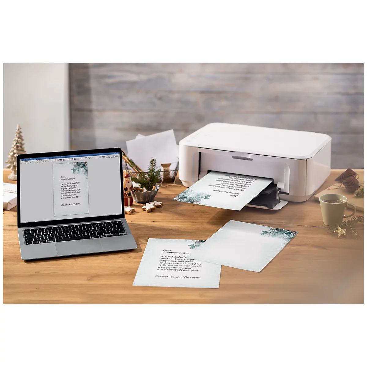 A laptop shows a printed document, next to it a white printer is printing more sheets. Finished sheets are lying on the table.