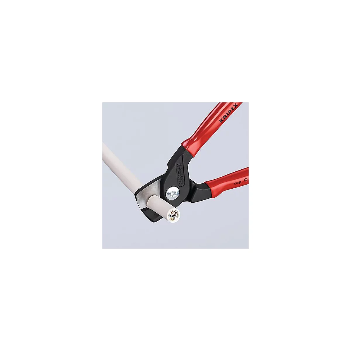 Pince coupante Knipex rouge coupant un câble. La section transversale du câble est visible.