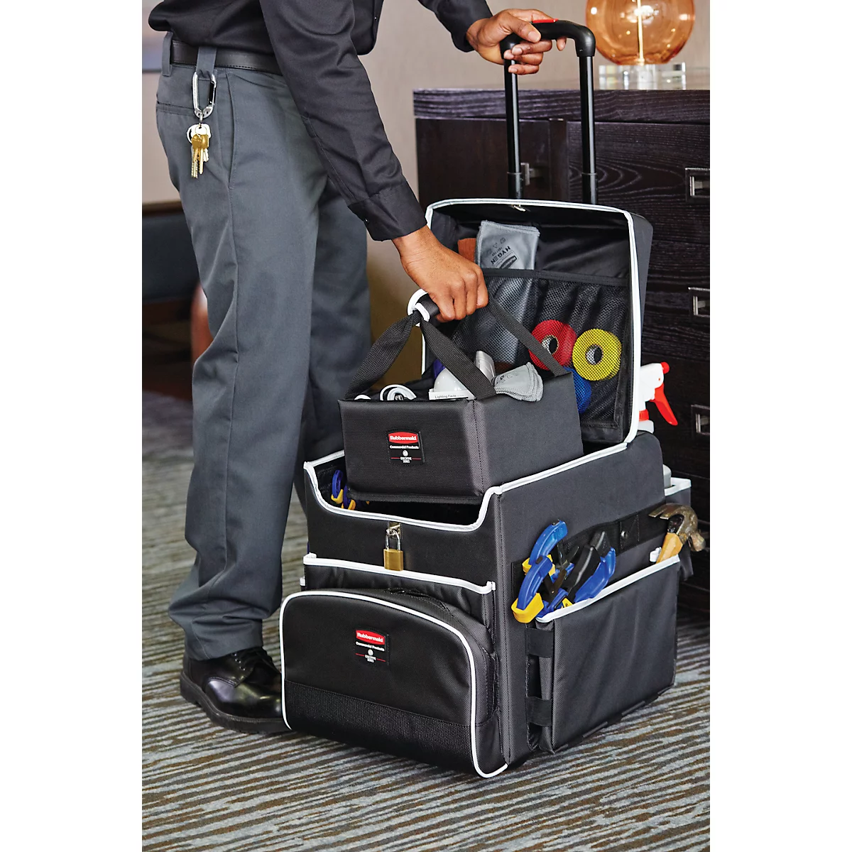 Person opening toolbox. Black toolbox with tools. Bunch of keys on pants.