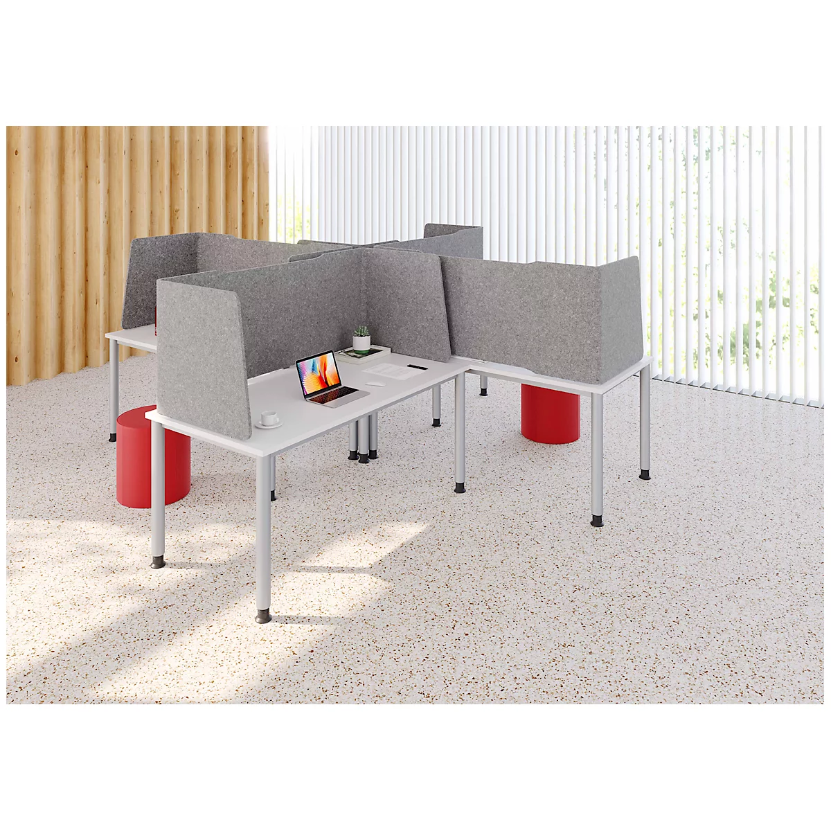 Plusieurs bureaux avec des cloisons grises, un ordinateur portable et des tabourets rouges.