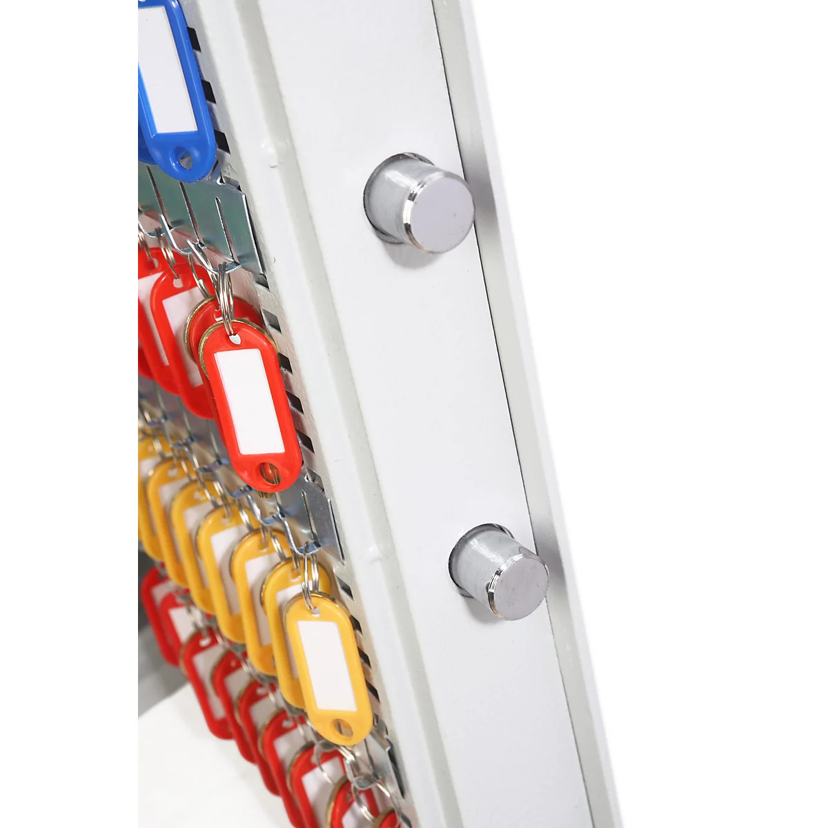 Gros plan sur les pênes de verrouillage d'une armoire à clés gris clair avec des porte-clés colorés.