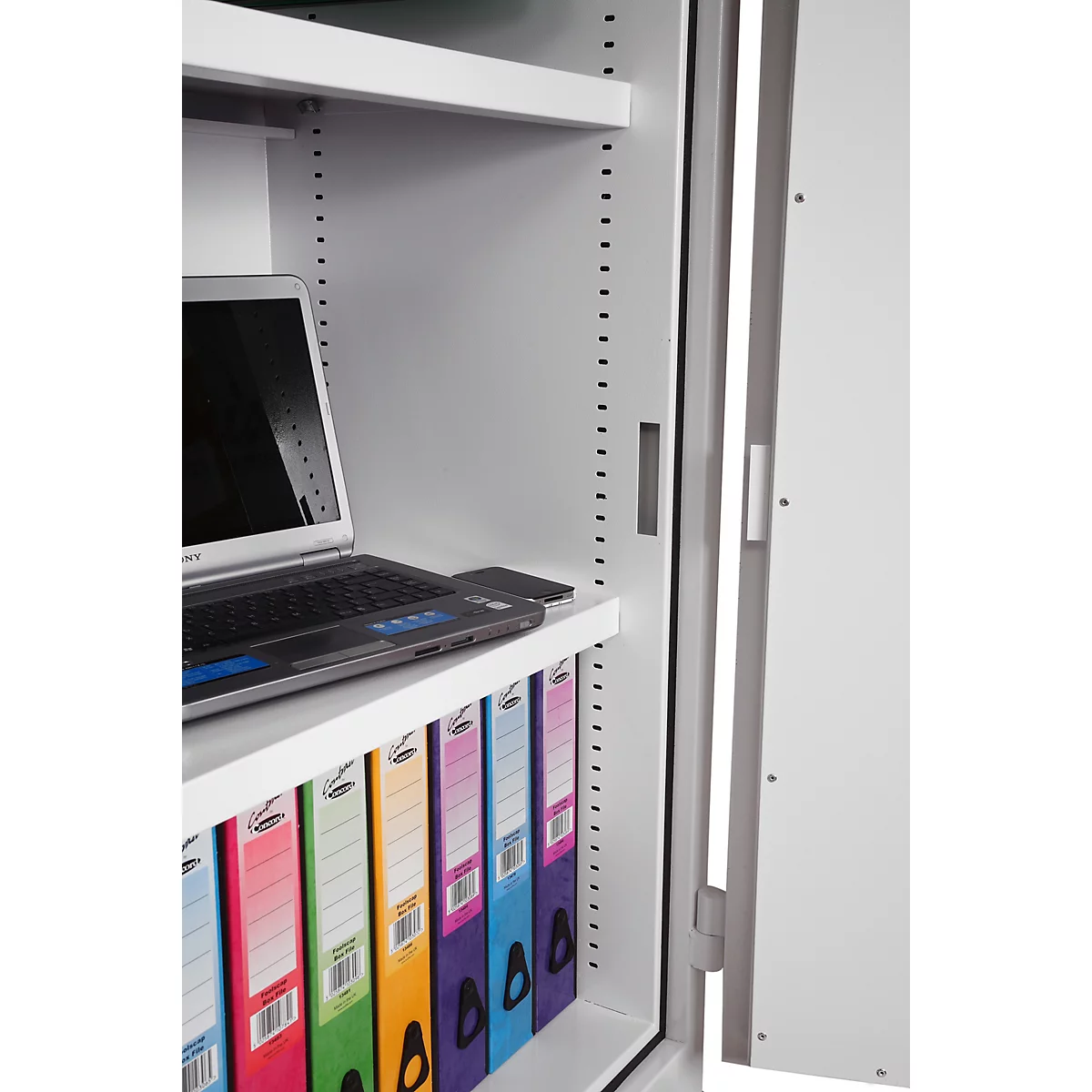 Armoire métallique blanche ouverte avec un ordinateur portable sur une étagère et des classeurs colorés en dessous.