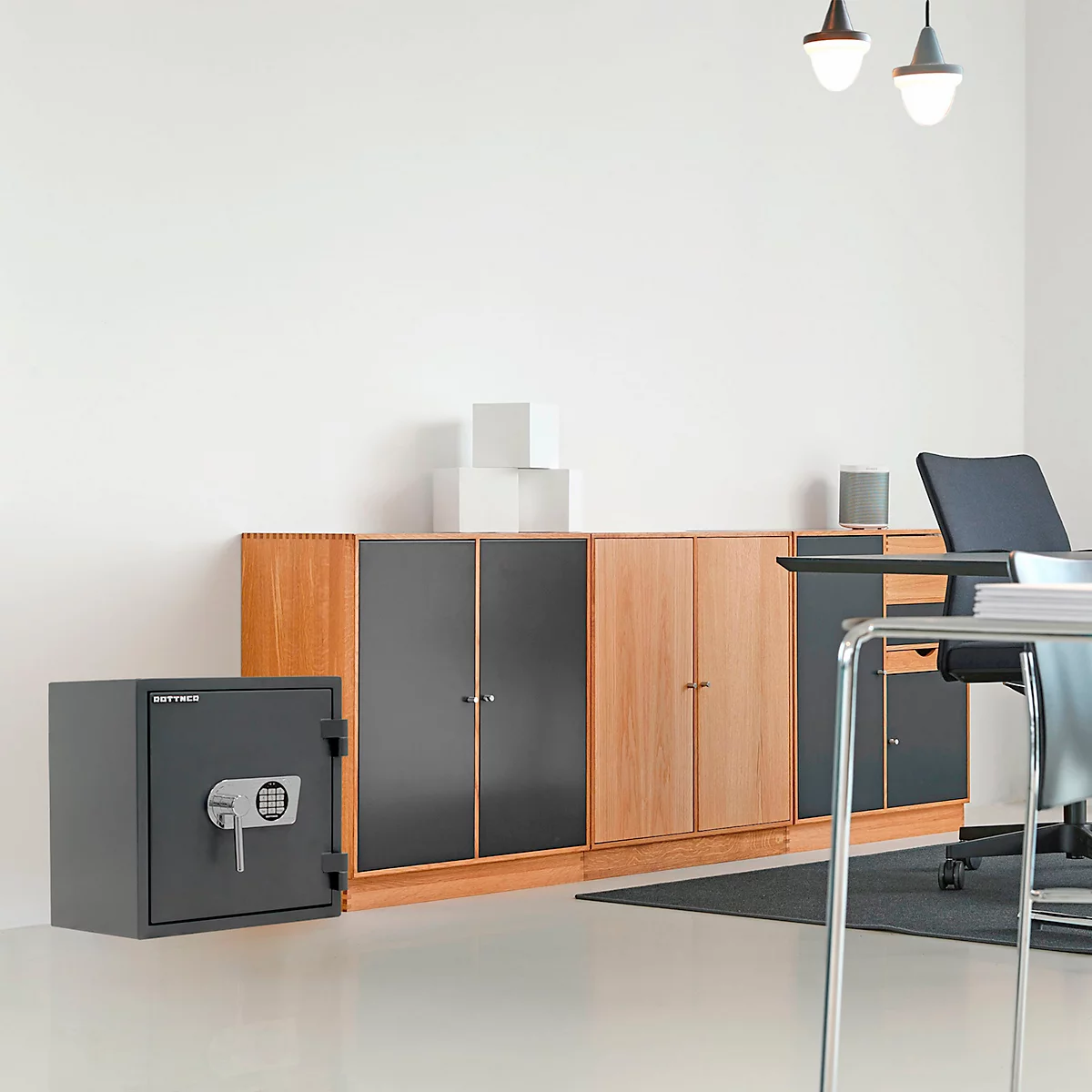 Coffre-fort gris avec clavier à côté d'une armoire. Un bureau et des lampes en arrière-plan.