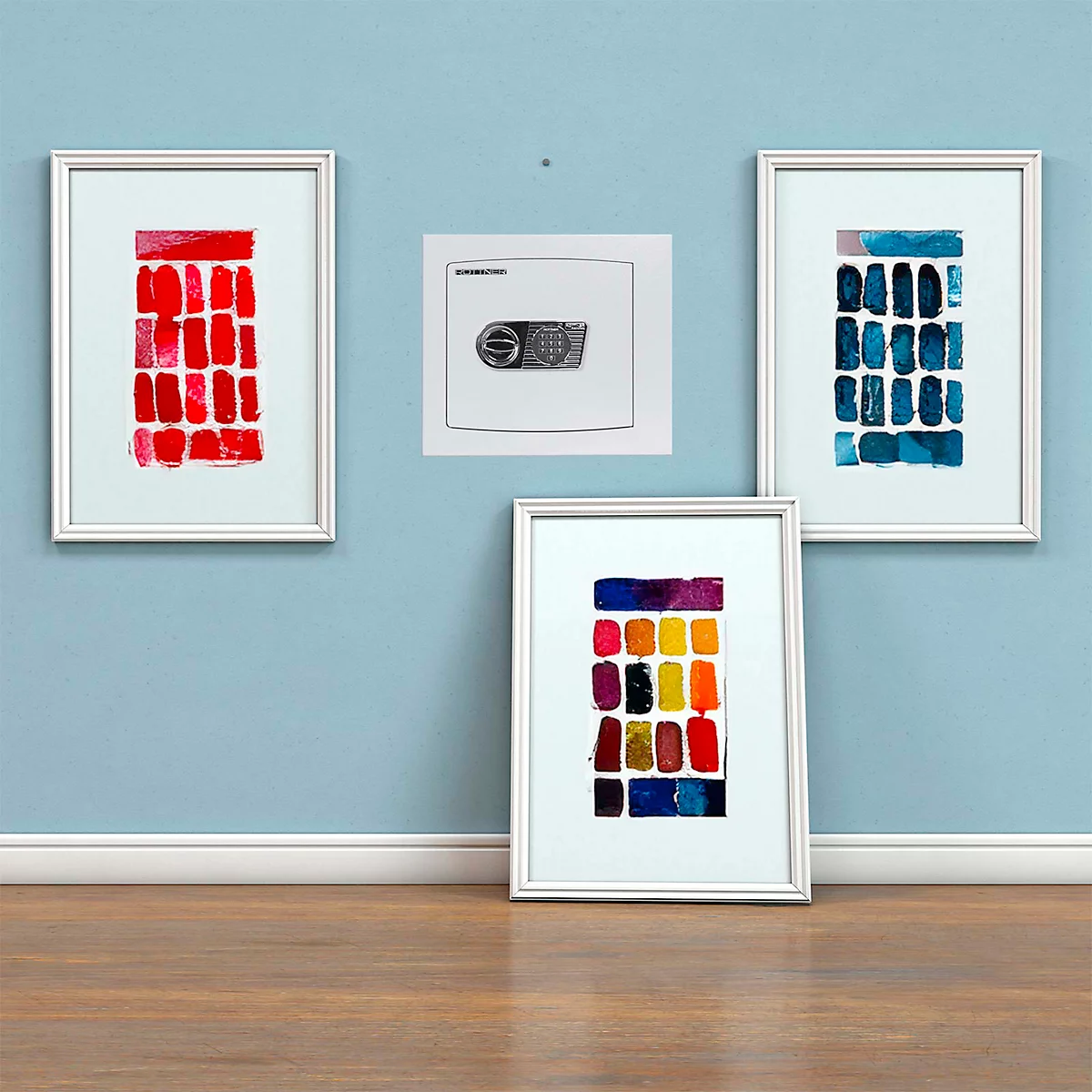 Quatre images encadrées accrochées à un mur bleu : un coffre-fort dans l'une, trois œuvres d'art abstraites.