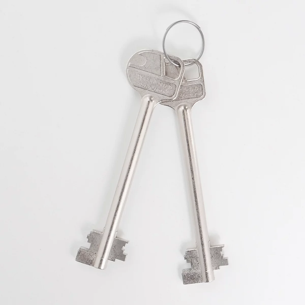 Deux clés argentées avec un porte-clés sur fond blanc.