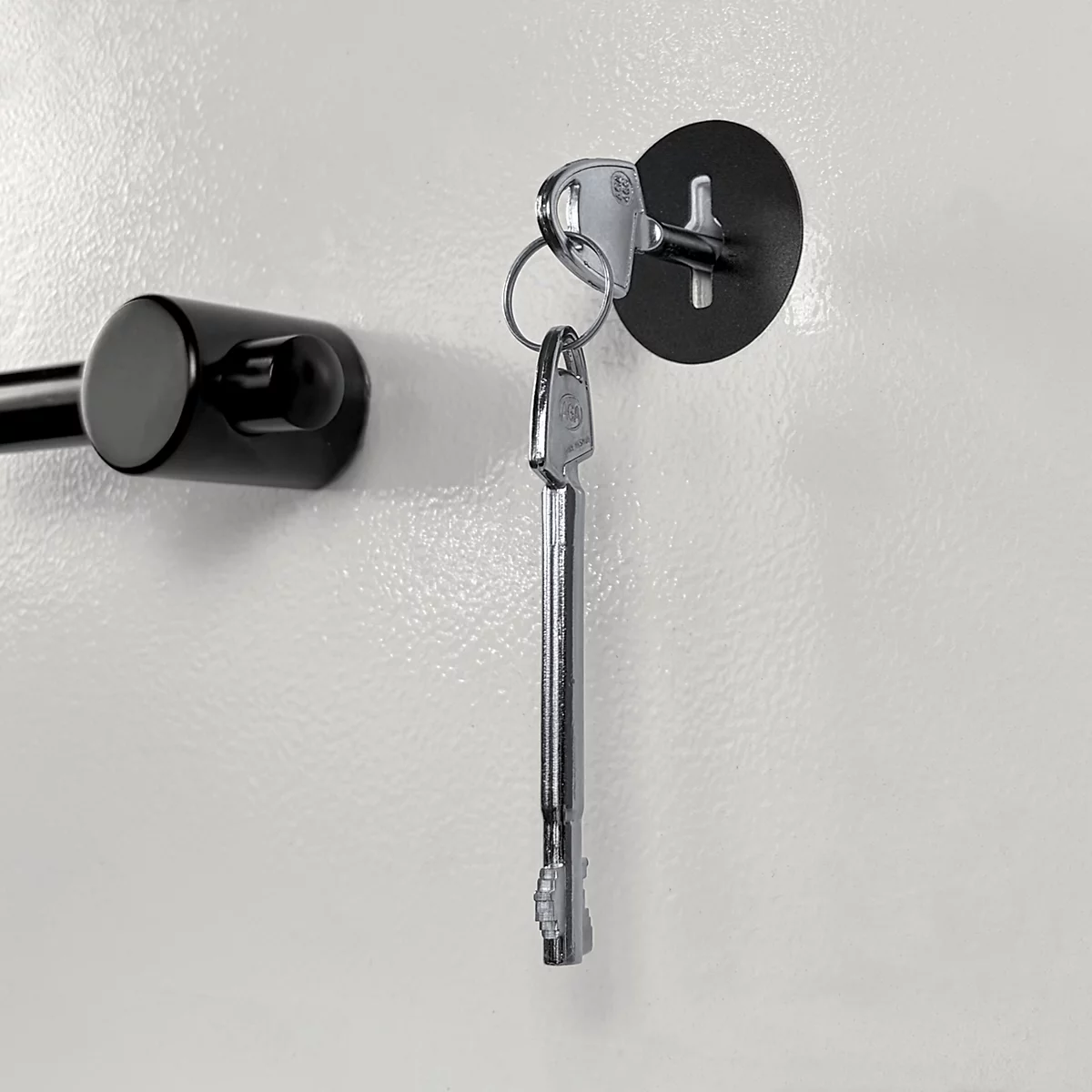 Une clé argentée est insérée dans une serrure noire ronde sur une surface claire et lisse.