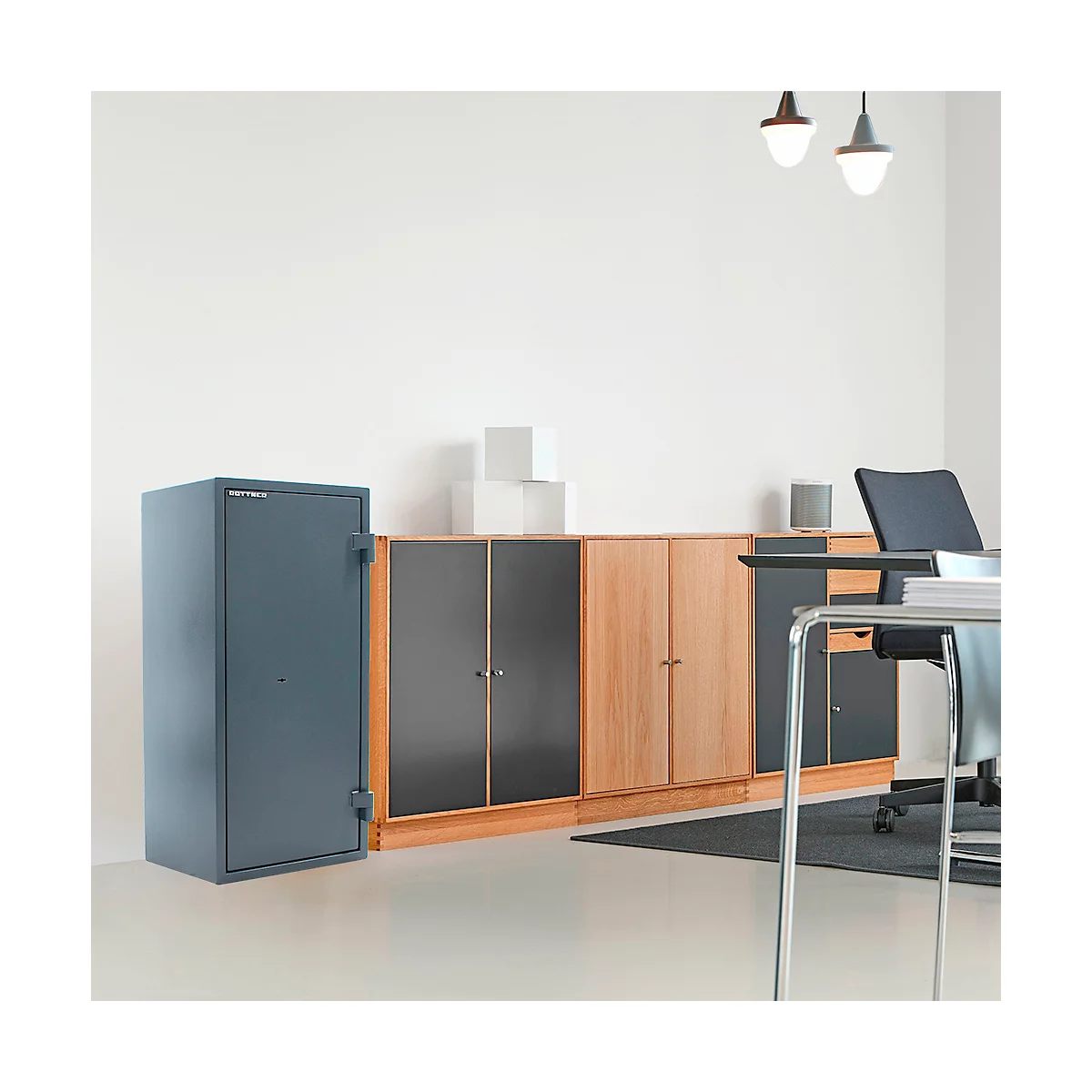Coffre-fort gris à côté d'une armoire dans un bureau, avec bureau et chaise derrière.