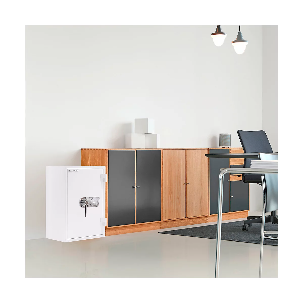 Coffre-fort blanc dans un bureau devant un buffet. Il y a une chaise de bureau à gauche.