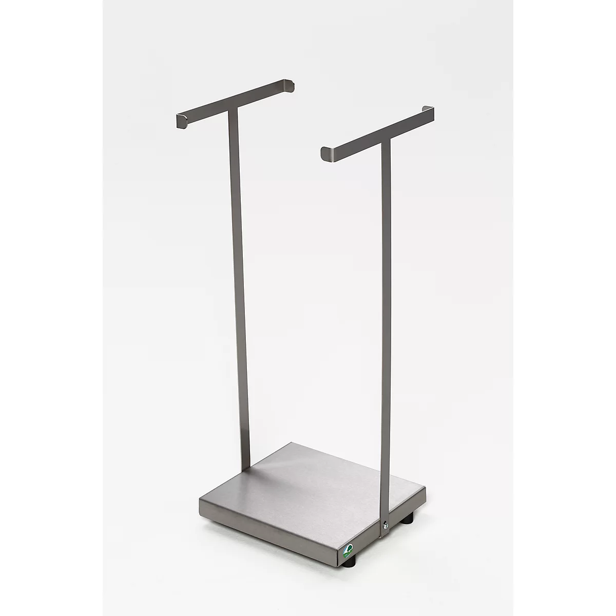 Soporte de ropa de metal gris, con dos soportes en forma de T. Se apoya sobre una base rectangular. Fondo neutro.