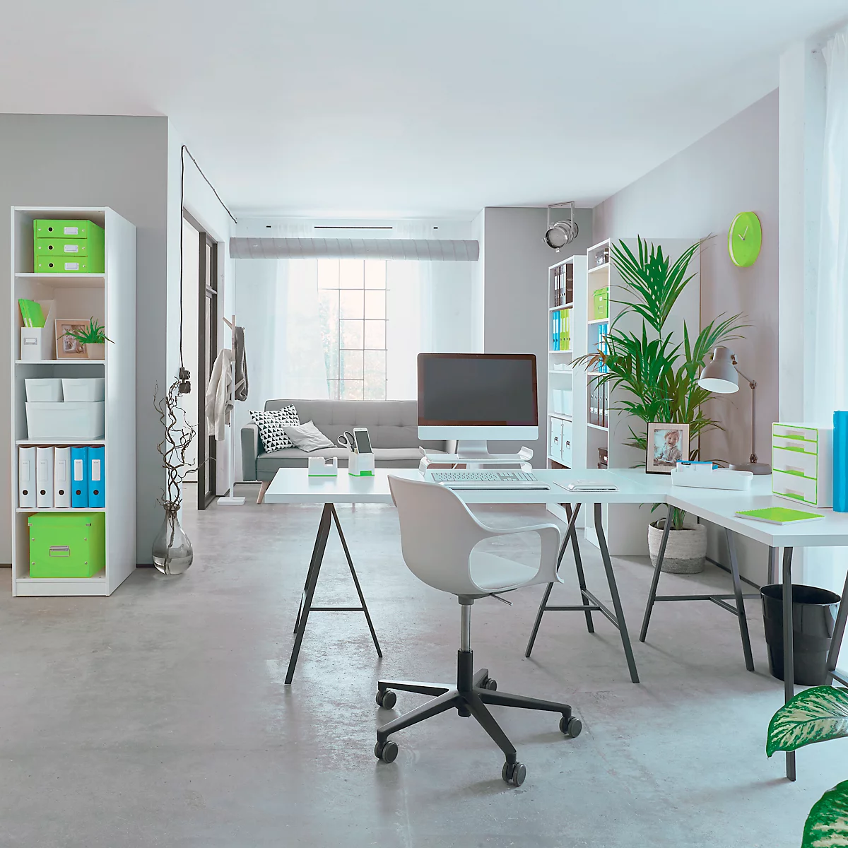 Ein helles Büro mit Schreibtisch, Stuhl und Computer. Im Hintergrund eine Couch.