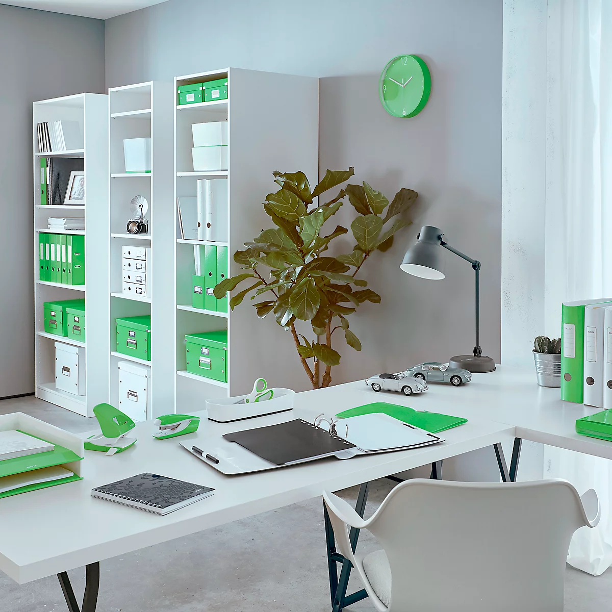 Modernes Büro mit grünen Akzenten: Schreibtisch, grüne Akten, grüne Uhr und Regal. Helle, freundliche Atmosphäre.