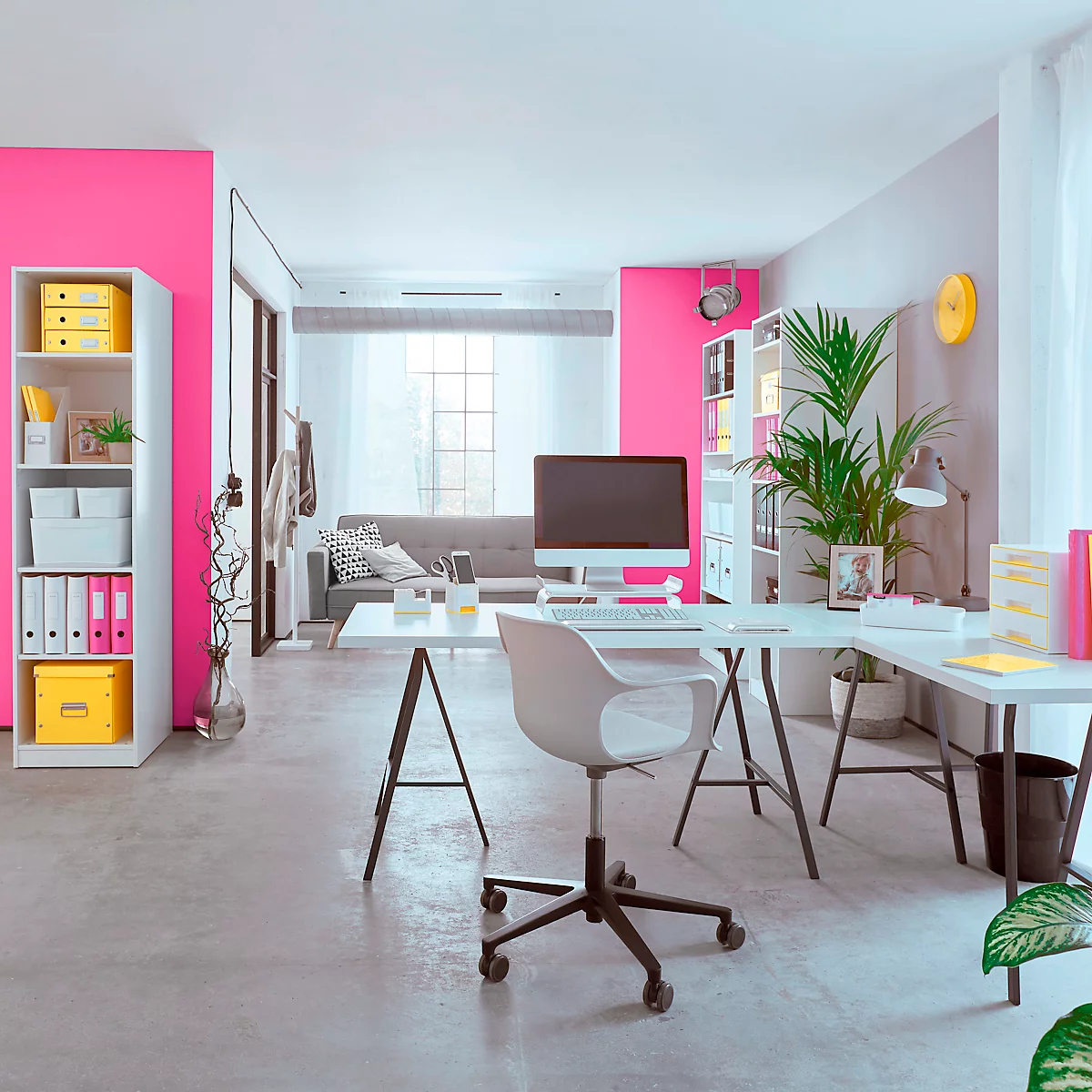 Modernes, helles Büro mit rosa Akzentwänden, Schreibtisch, Bürostuhl und Pflanzen. Im Hintergrund ist ein Sofa zu sehen.