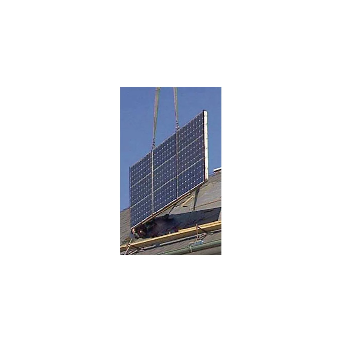 Un grand panneau solaire est installé sur un toit par une grue.