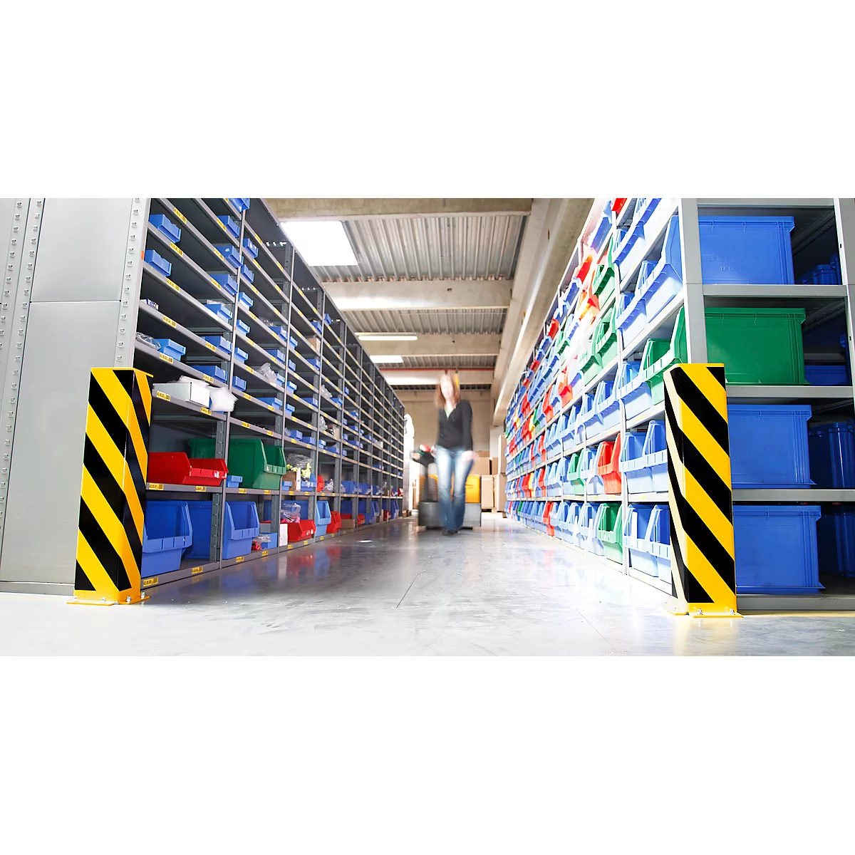 Warehouse with shelves, colorful containers. A person walks down the aisle.