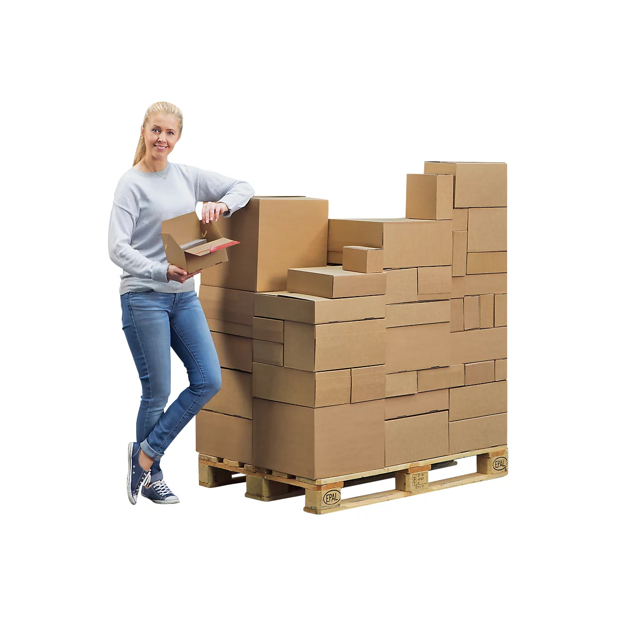 Een glimlachende vrouw leunt tegen een pallet vol met diverse kartonnen dozen.
