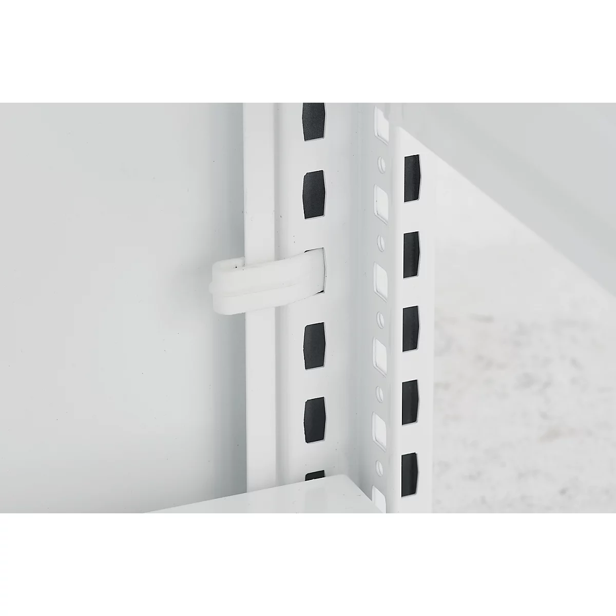 Gros plan sur un système d'étagères blanc. Un clip en plastique blanc maintient une partie d'étagère blanche.