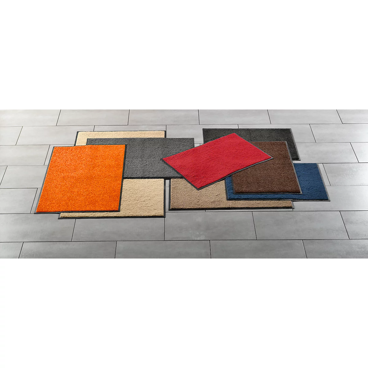 An arrangement of different colored carpet tiles on a gray tiled floor.