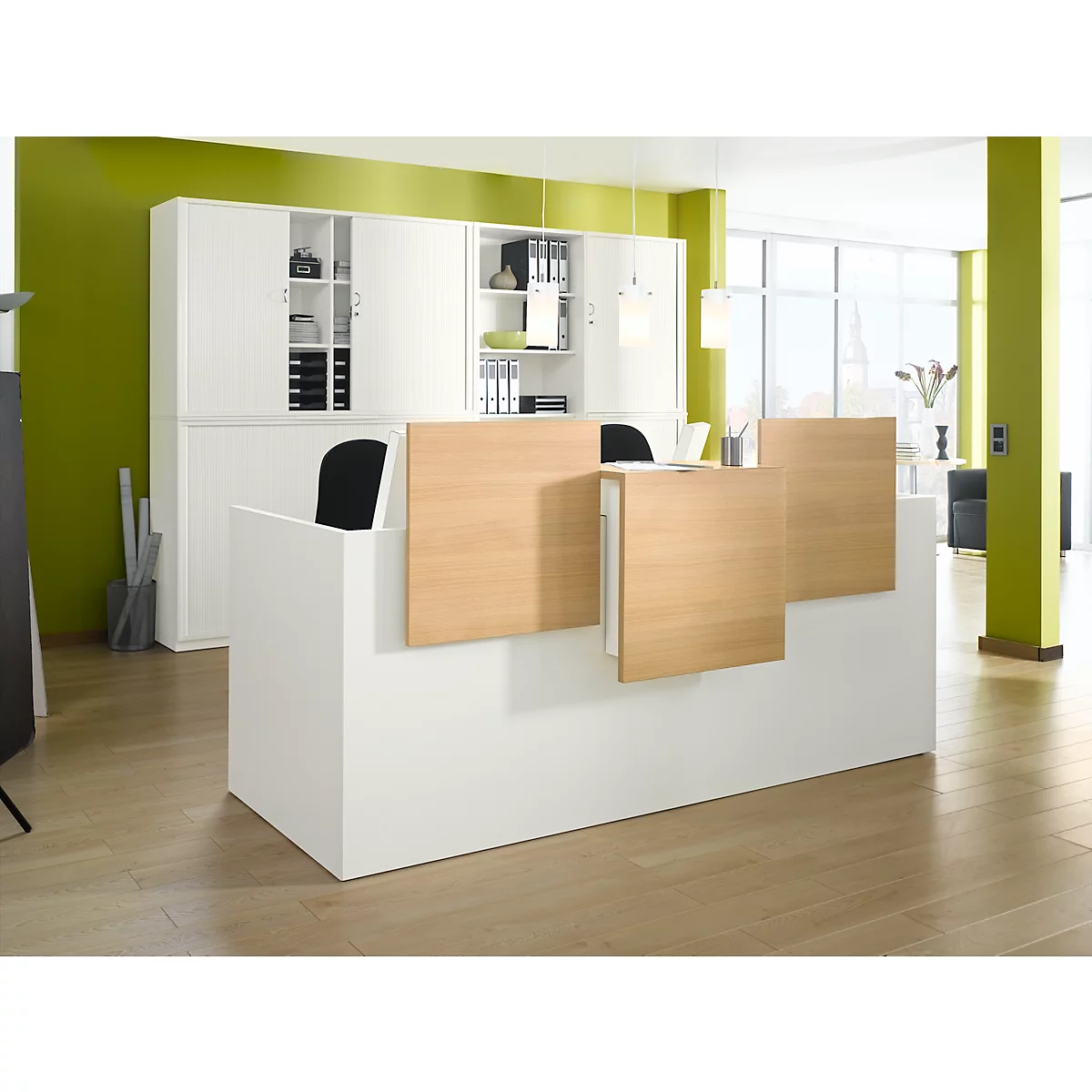 Un comptoir de réception blanc avec des éléments en bois et des chaises noires. En arrière-plan, des armoires blanches et un mur vert.