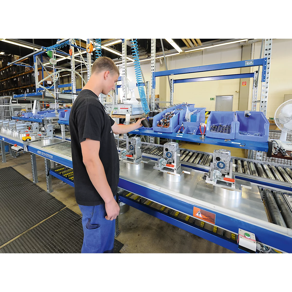 Un hombre trabaja en una cadena de montaje en una fábrica. Observa un dispositivo montado.