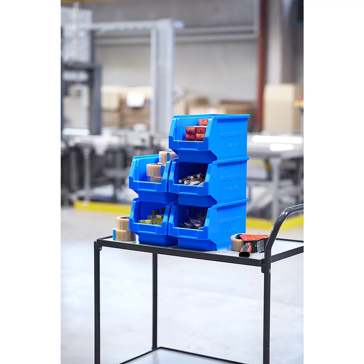 Cajas de almacenamiento azules en un carro de herramientas. Varias piezas pequeñas están dentro. Entorno de taller.