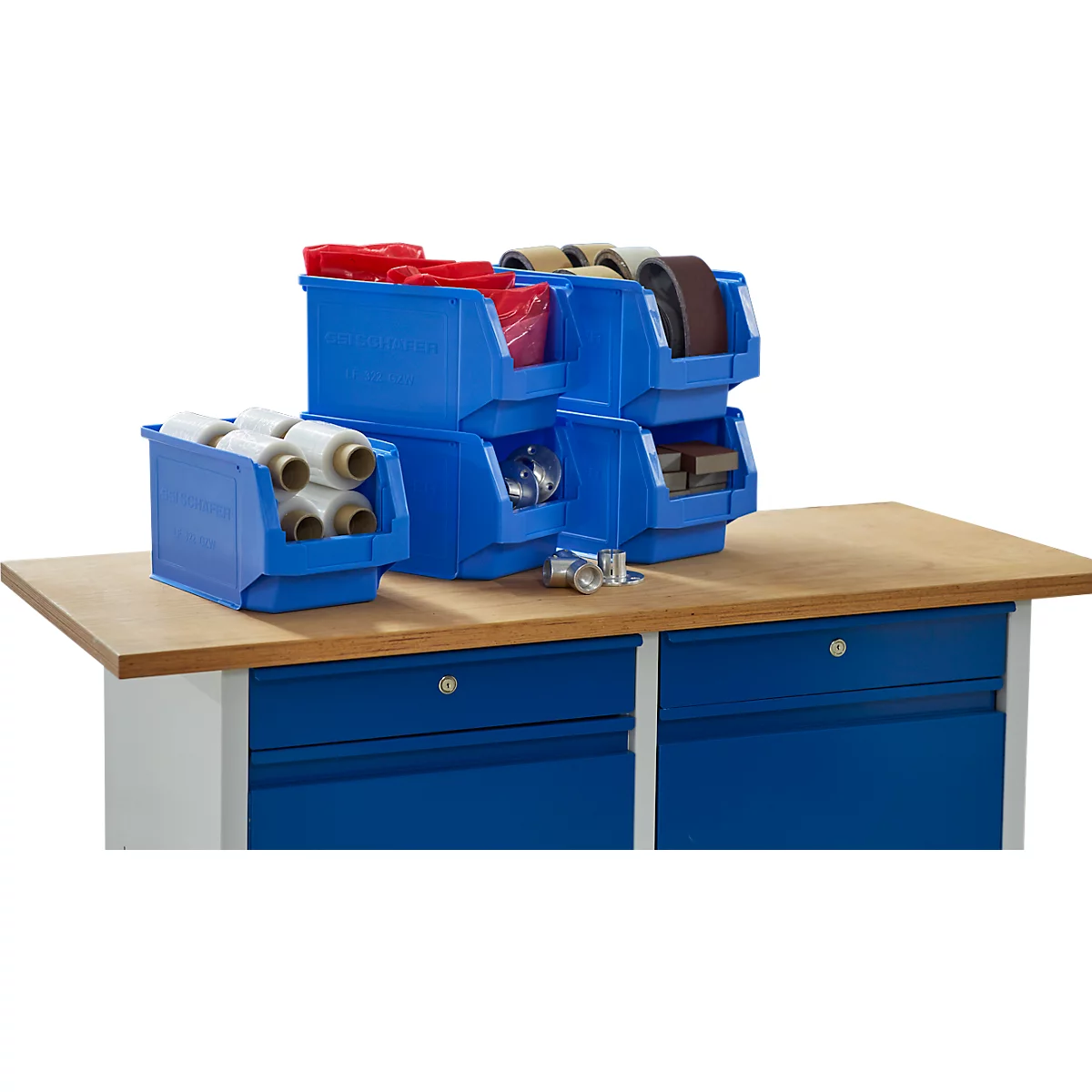 Cajas de plástico azul con herramientas en un banco de trabajo de madera. Rollos en primer plano. Bandas de lijado y tornillos en el fondo.