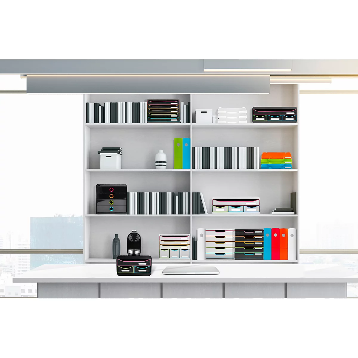 Bureau blanc avec étagères remplies de livres et de fournitures de bureau. Sur le bureau, des systèmes de classement de différentes couleurs.