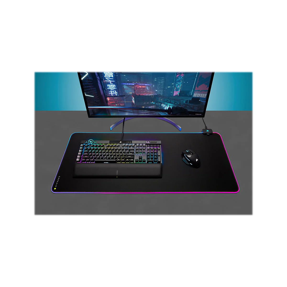 Ein Gaming-Setup mit Tastatur, Maus, Mauspad und Monitor. Der Monitor zeigt eine Stadt bei Nacht. Das Setup ist auf einem grauen Tisch.