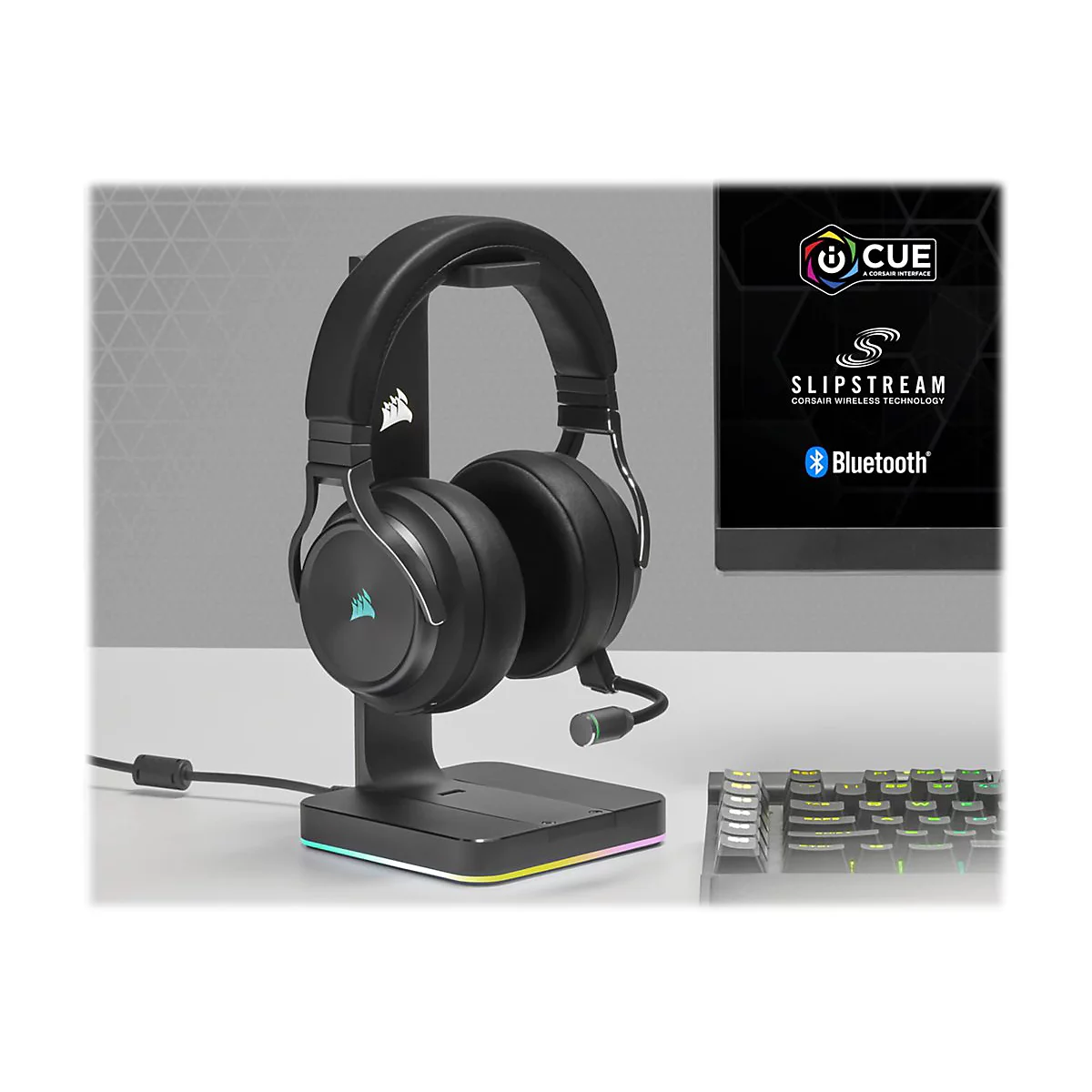 Schwarzes Headset auf einem Ständer, Display mit Logo-Elementen, beleuchtete Tastatur im Hintergrund.
