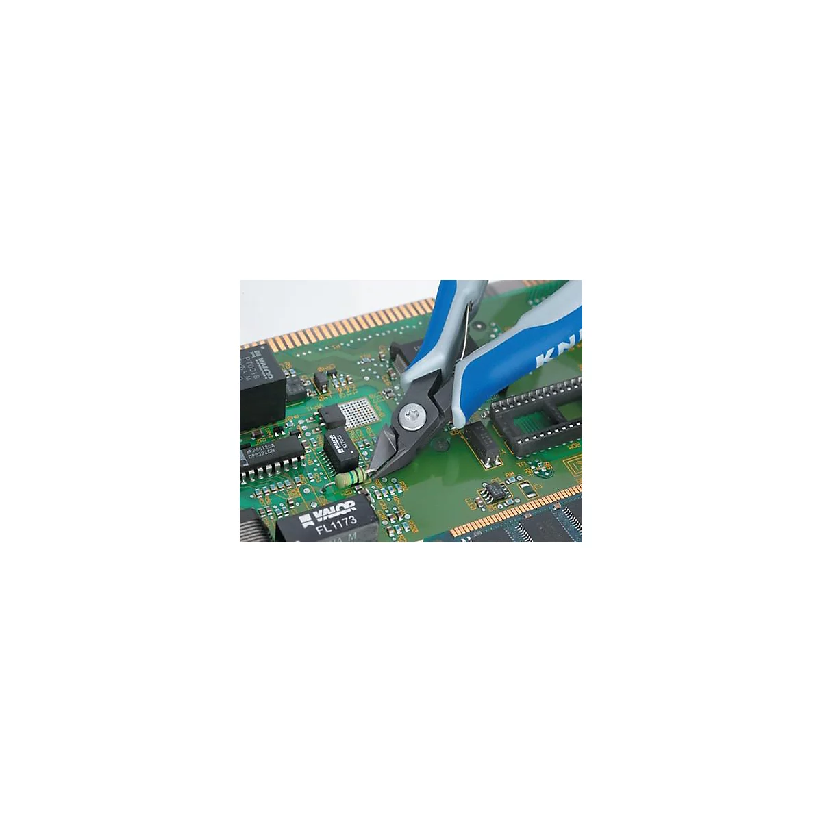 Une pince coupante coupe un fil sur une carte de circuit imprimé verte. Poignée bleue, logo "KNIPEX" visible.