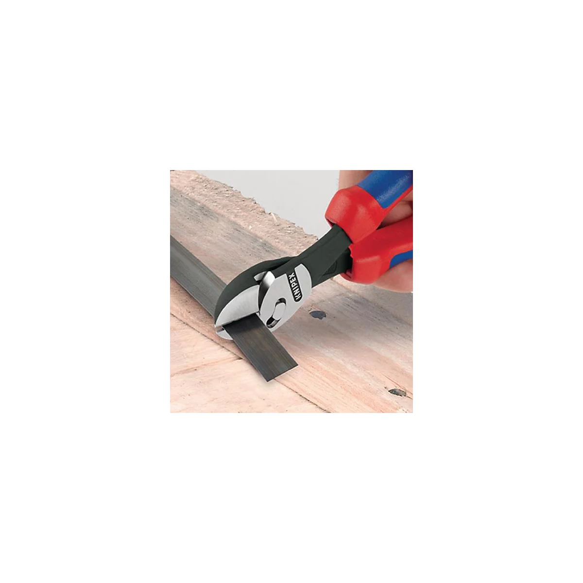 Pince coupante coupant du métal. L'outil a des poignées rouges et bleues et est placé sur une planche de bois.