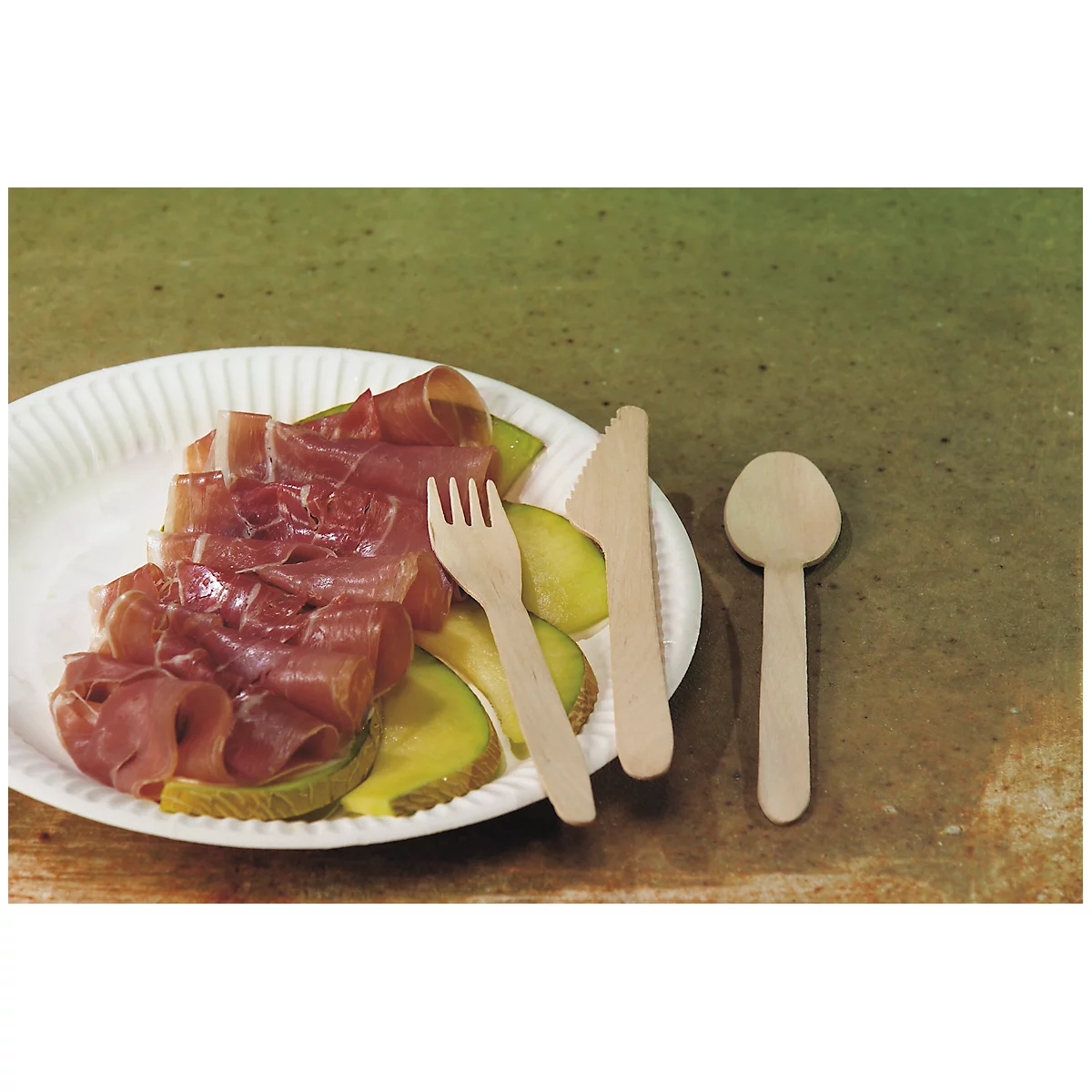 Une assiette avec du prosciutto et du melon, à côté d'une fourchette, d'un couteau et d'une cuillère en bois.