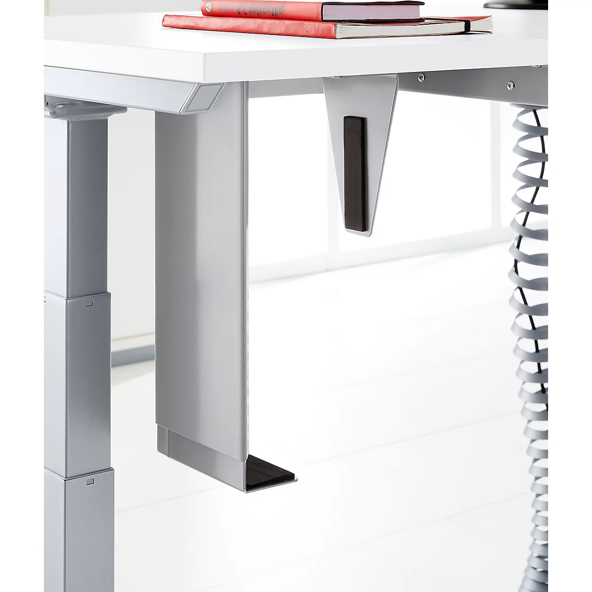 Close-up of a white desk with gray metal legs and black details. Books are on the tabletop.