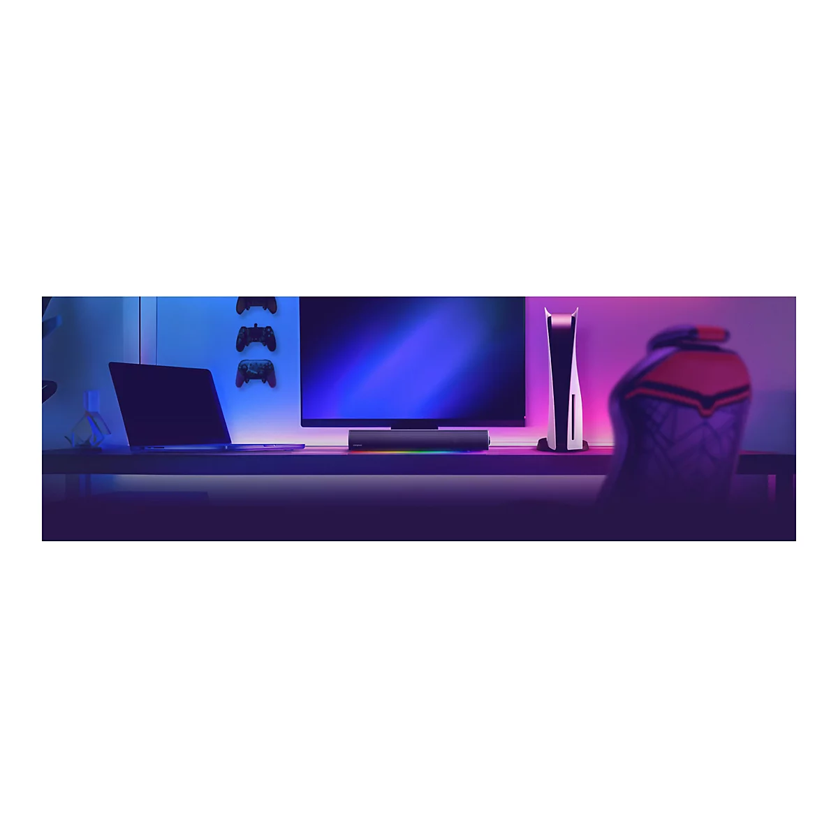 Schreibtisch mit Laptop, Monitor, Playstation, Soundbar und Gamern eingerichtet.