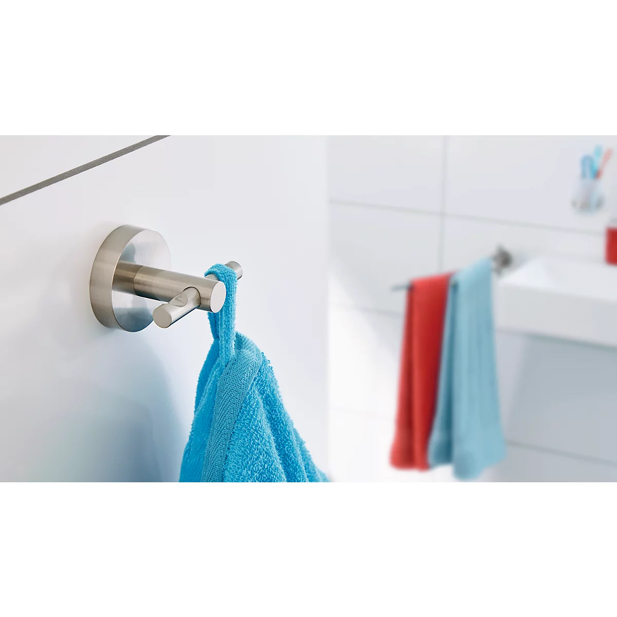 Un porte-serviettes métallique est accroché à un mur blanc ; une serviette bleue y est accrochée.