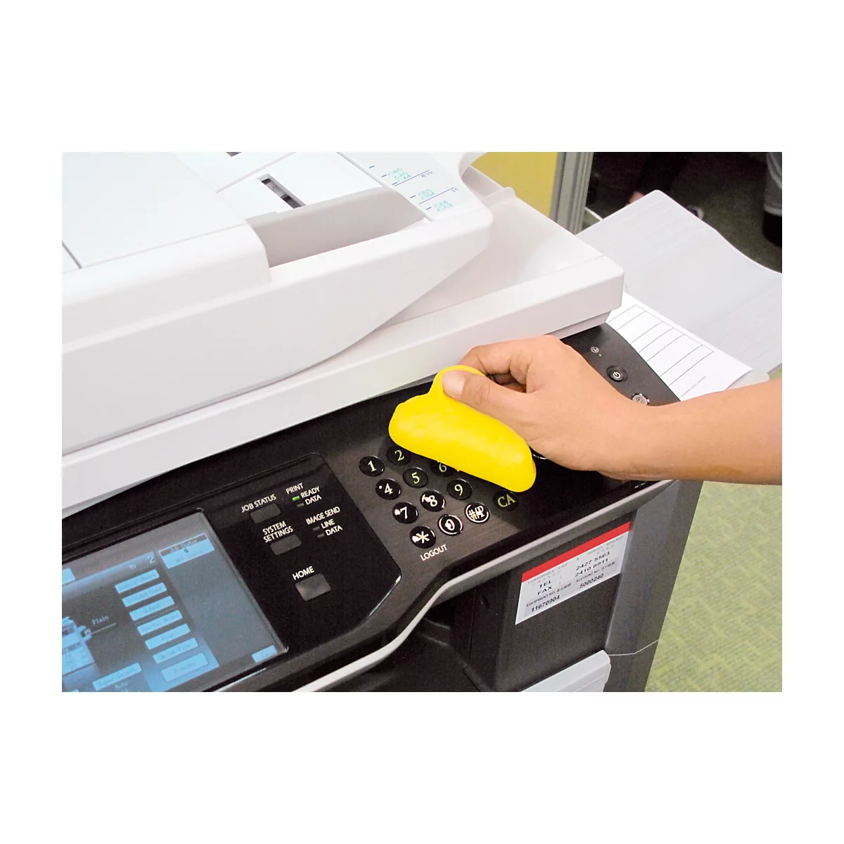 A hand presses a yellow button on a copier. Numbers and symbols can be seen on the control panel.