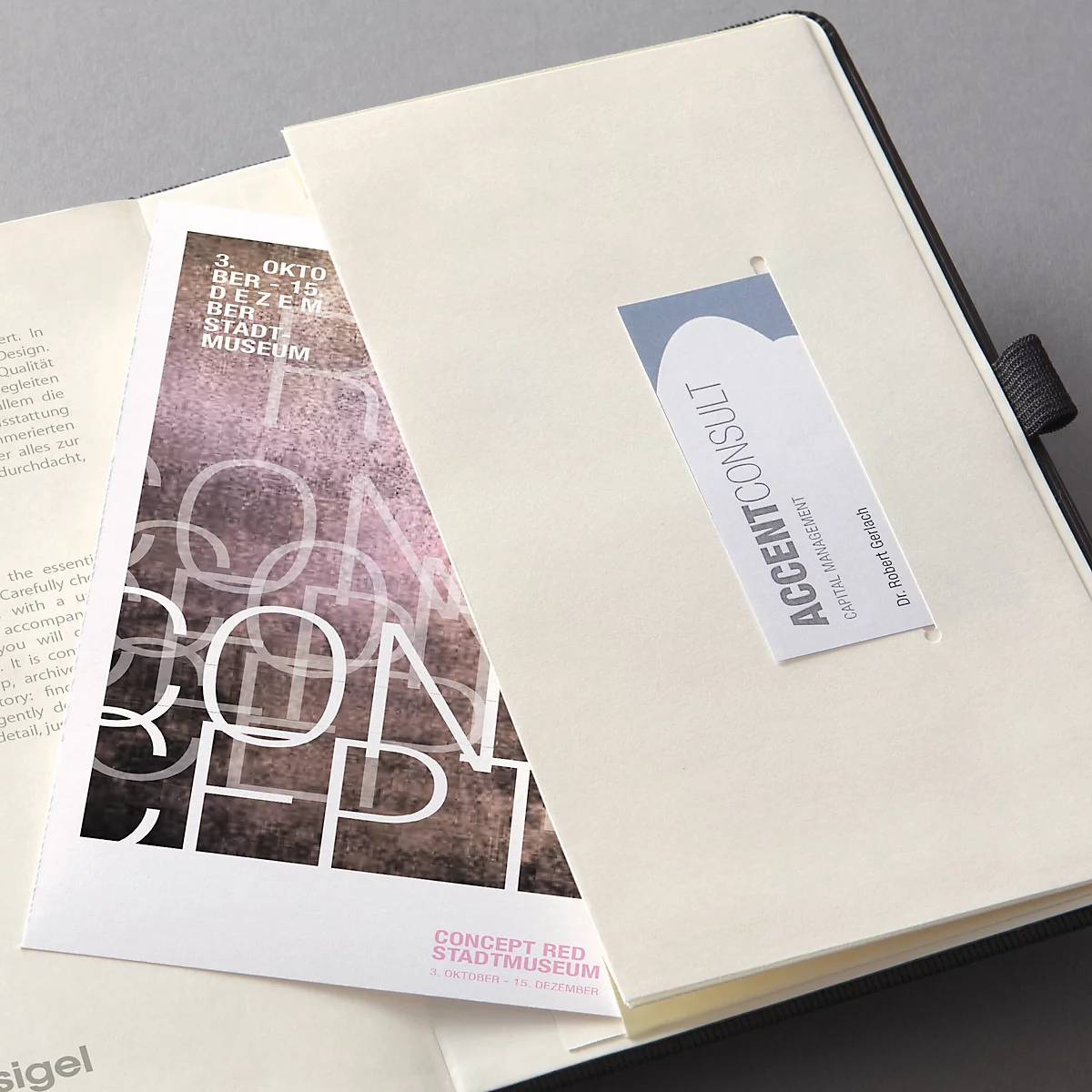 Notitieboek met visitekaartje en flyer. Op de flyer staat 'CONCEPT'.