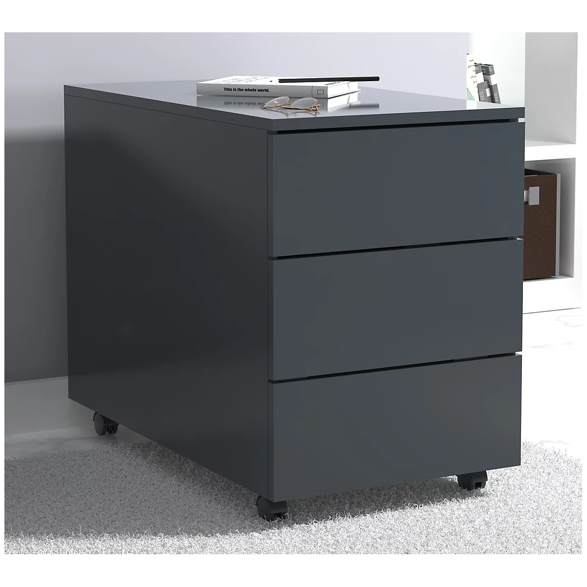 Dark gray rolling cabinet with three drawers. A book and glasses are on top.