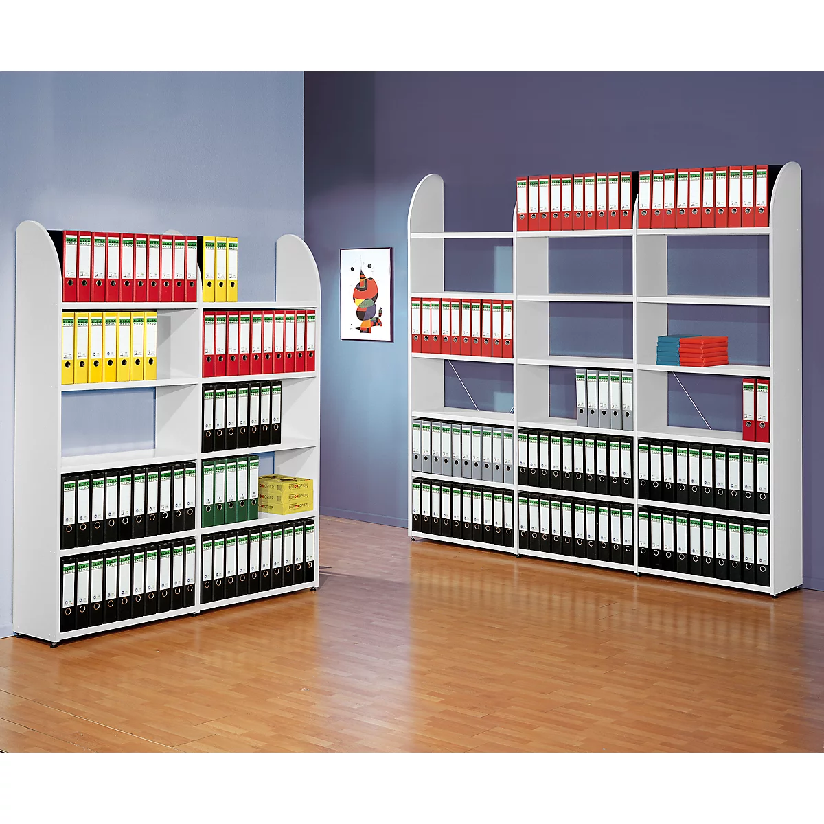 Two white file cabinets stand on wooden floors. Filled with colorful folders. A framed picture hangs on the wall.