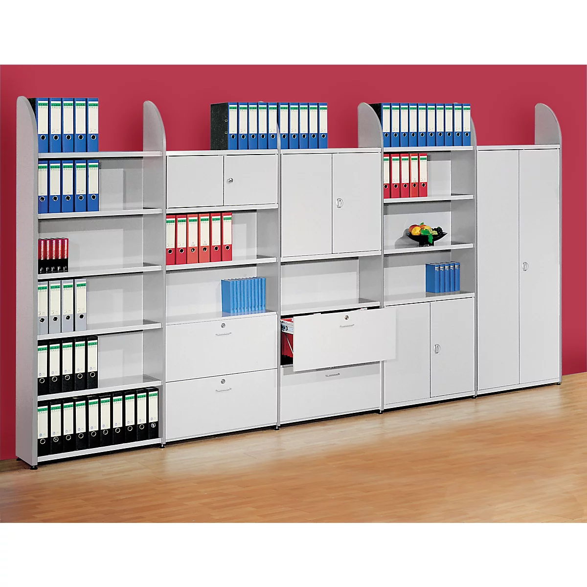 White office furniture wall with files and cabinets. On a red background in front of a light floor.