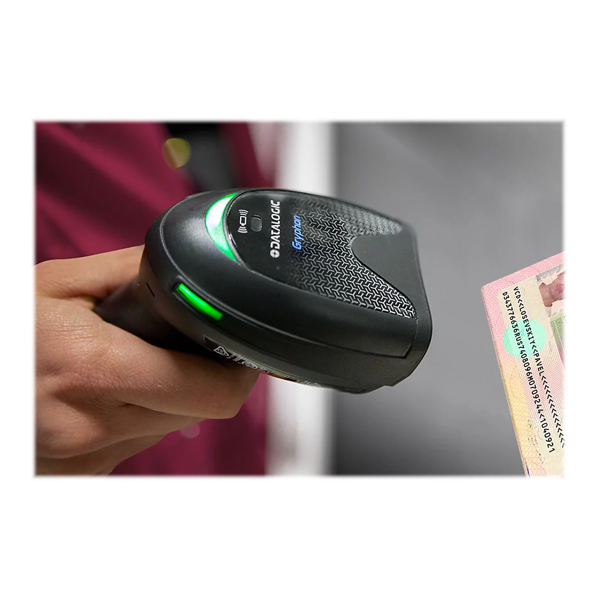 Une main tient un lecteur de code-barres noir de la marque Datalogic, au-dessus d'une carte d'identité.