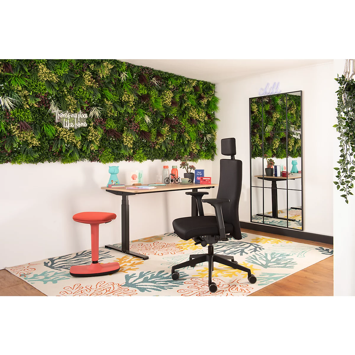 Büro mit Schreibtisch, Stuhl, rotem Hocker und Wand mit Pflanzen. Spiegel und Dekorationen sind sichtbar.