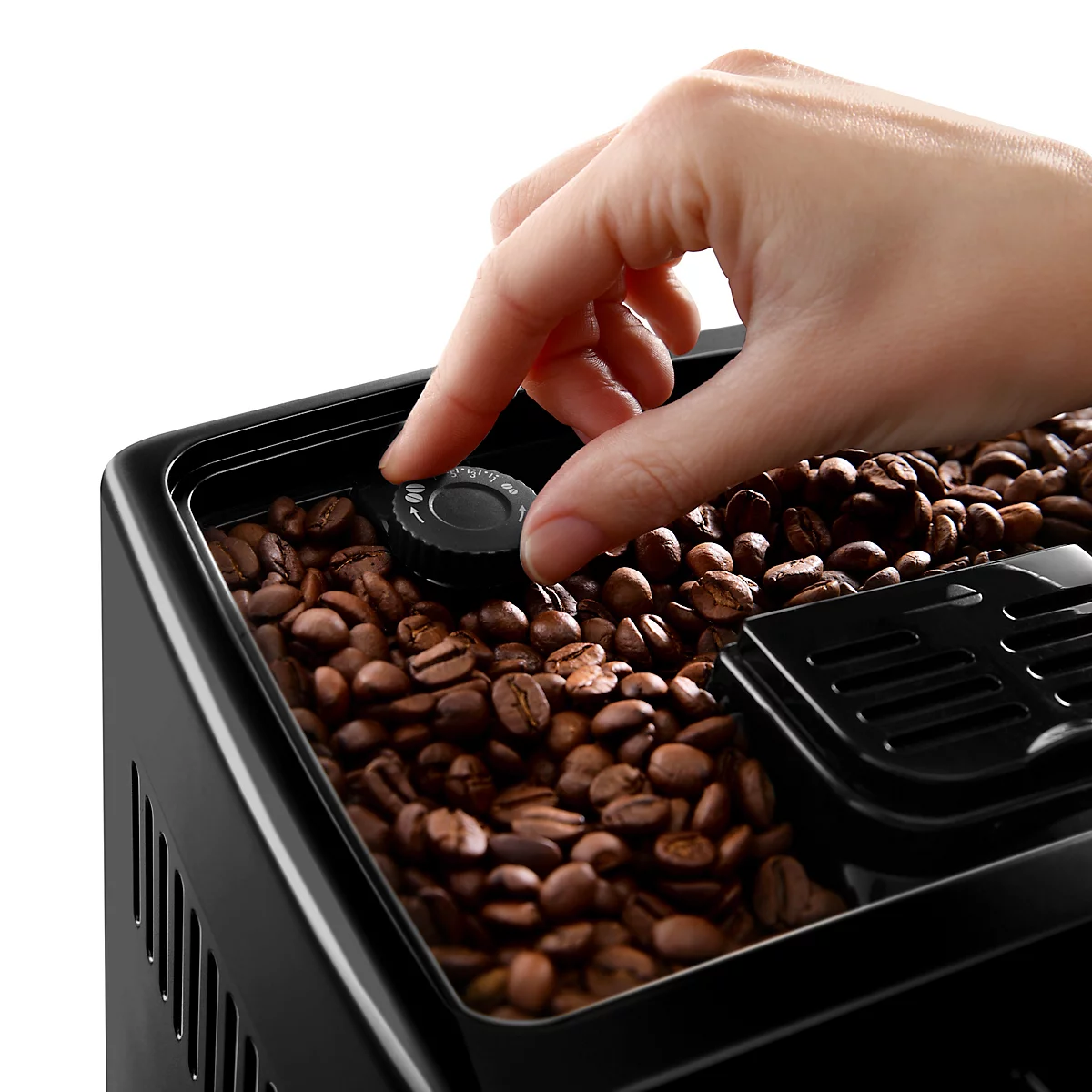 Nahaufnahme: Eine Hand dreht einen schwarzen Knopf auf einer Kaffeemühle. Die Mühle ist mit Kaffeebohnen gefüllt.
