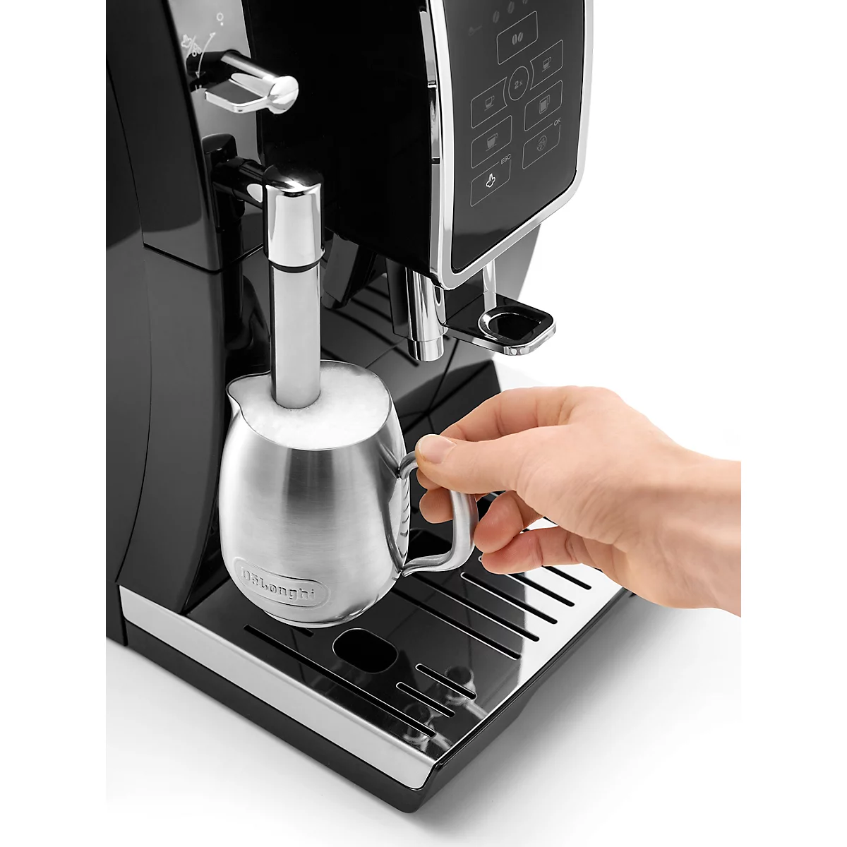 Nahaufnahme einer Espressomaschine mit Milchaufschäumer. Eine Hand hält eine Kanne mit aufgeschäumter Milch.