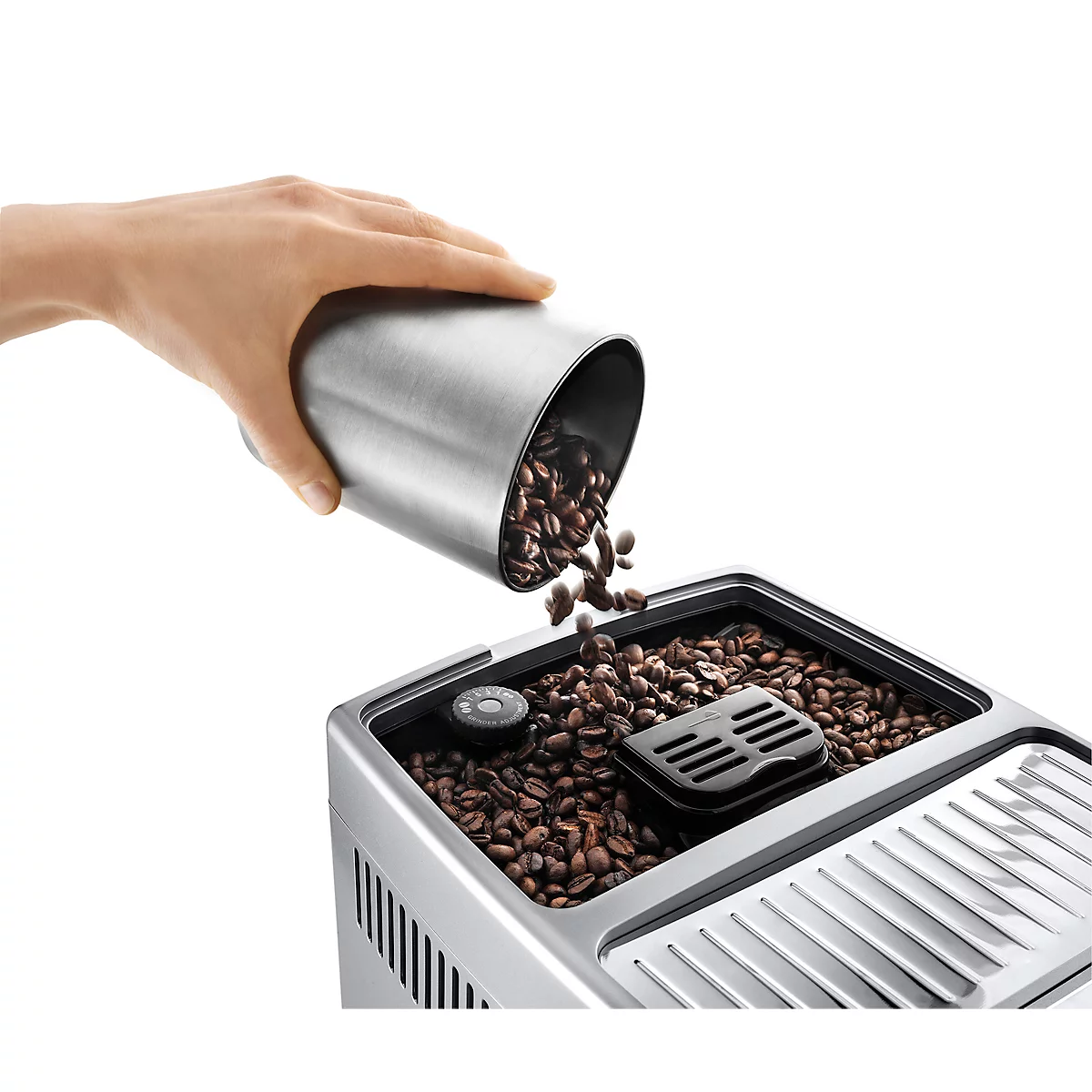 Hand gießt Kaffeebohnen aus einem silbernen Behälter in eine Kaffeemaschine.