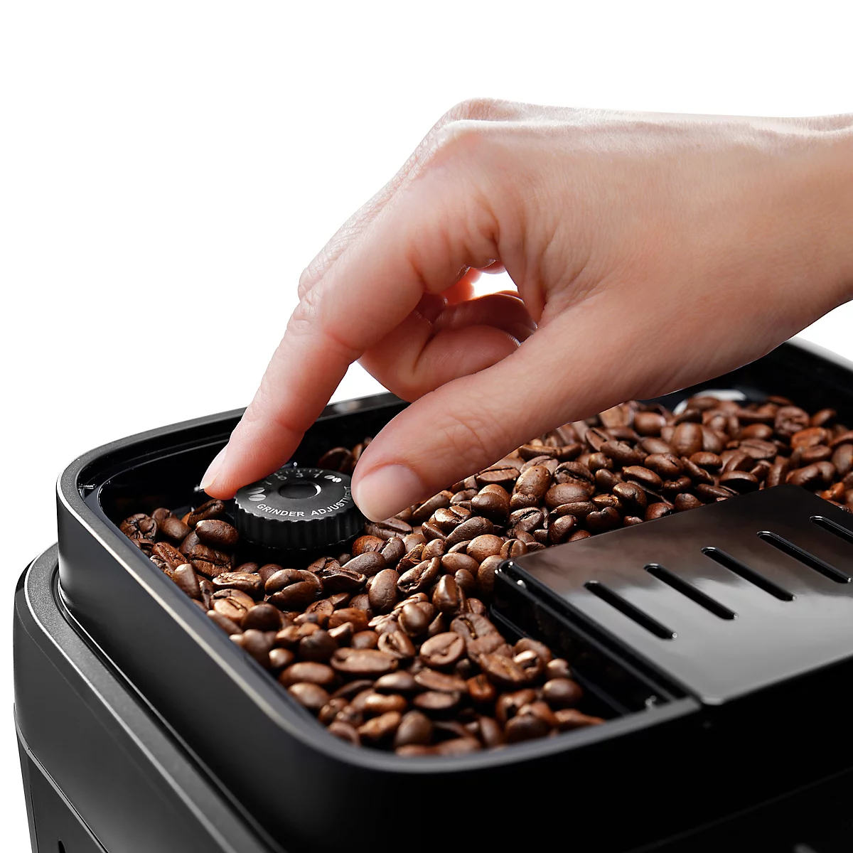 Nahaufnahme: Hand berührt Regler in einem Kaffeebohnenbehälter. Dunkle Kaffeebohnen füllen den Behälter.