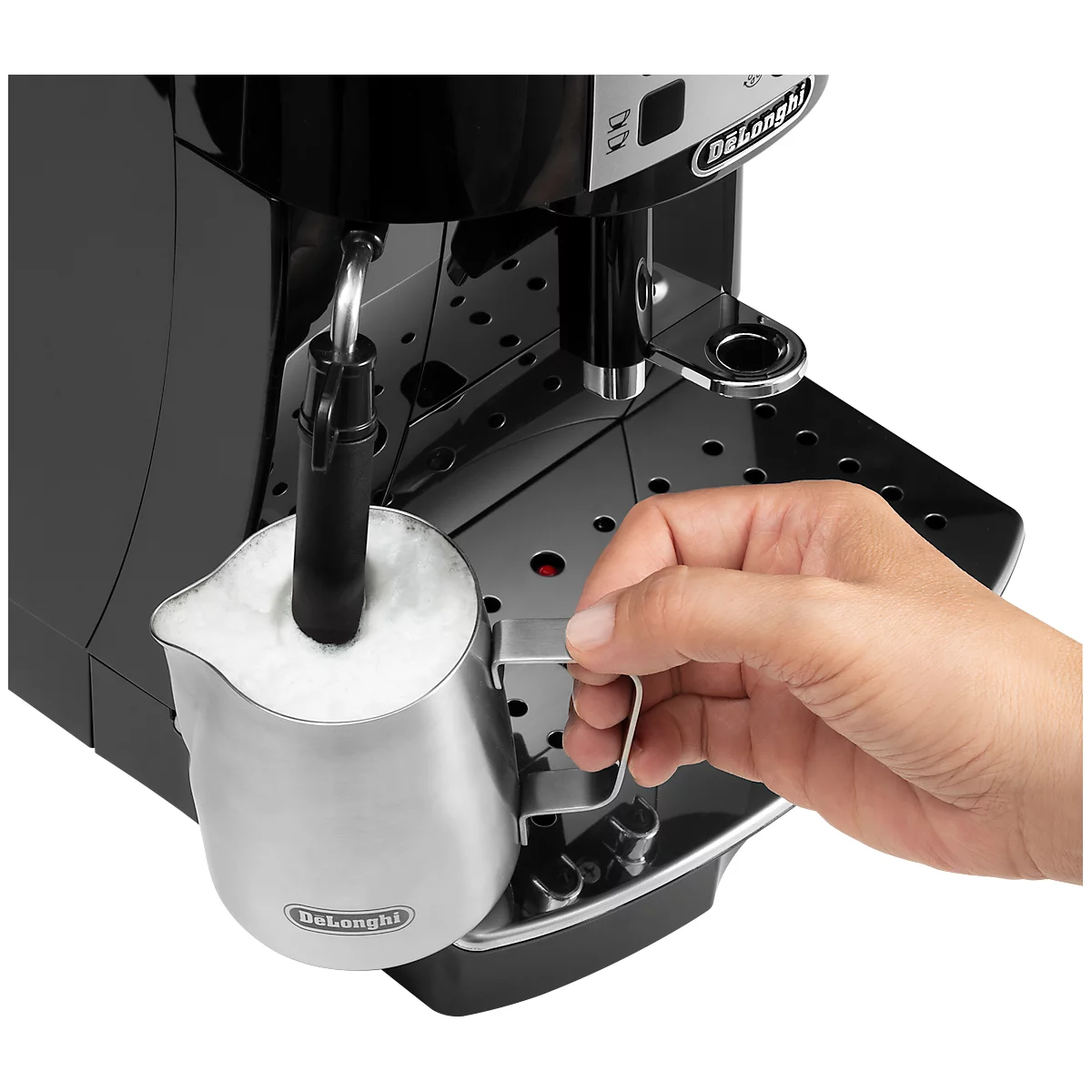 Nahaufnahme einer schwarzen Kaffeemaschine mit Milchschaum in einer Kanne. Eine Hand hält die Kanne.