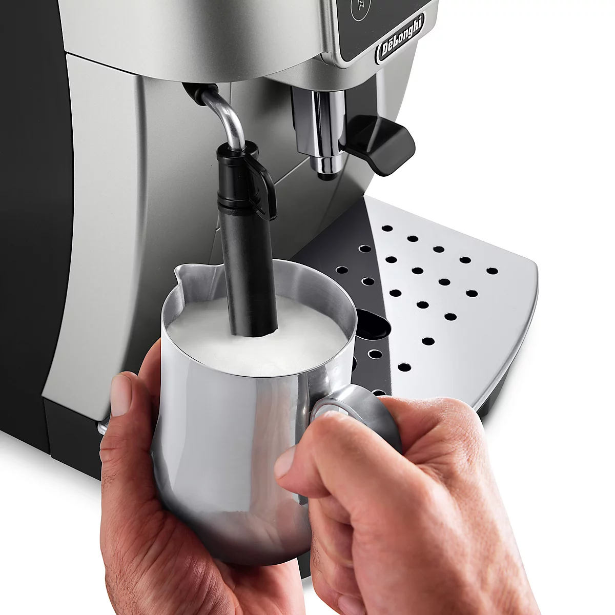 Nahaufnahme einer Espressomaschine beim Milchaufschäumen in einem Metallkännchen.